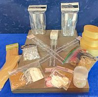 Overview of lot showing champagne flutes, ribbon rolls, wood sticks, wood boxes, bead strands, pearls, tags, twine, tape and jar
