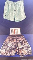 Two pairs of swim trunks and watch band pack displayed