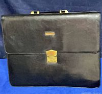 Front view of black leather briefcase showing gold latch and nameplate