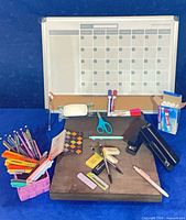 Lot overview showing planner board, writing instruments, staplers, scissors, basket