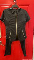 Front view of black scrub top and pants on hanger