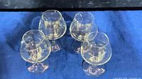 Four clear glass snifters on blue cloth, side view