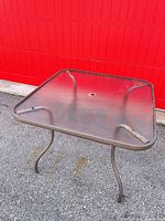 Top view of square glass patio table showing umbrella hole and frame