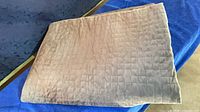 Folded gray quilted coverlet on blue surface