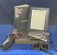 Lot overview showing book, leather frame, two sunglasses and cases