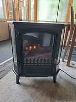 Front view of black electric stove fireplace with flame effect visible