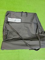Exterior of folded black storage bag with handles and strap visible