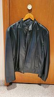 Front view of black leather jacket on hanger