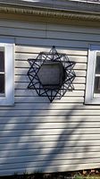 Mirror mounted on exterior siding showing full starburst design