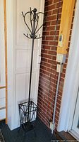 full view of black metal coat and umbrella stand against wall