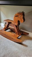 front-left view of wooden rocking horse showing seat, head profile, rockers