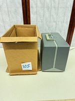 Closed gray carrying case beside cardboard box