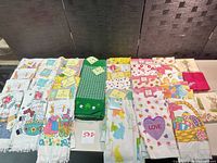 Wide view showing approximately 18 assorted holiday cotton kitchen towels laid out