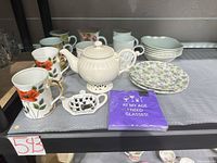 Full lot showing teapot, mugs, bowls, plates, cups, teabag holder and napkins