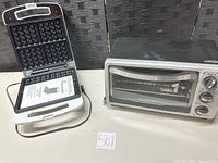 Toaster oven and waffle maker side by side on table