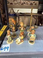 Group shot of six Hummel figurines, beer stein, brass scale