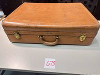 Top view of tan leather Hartmann suitcase with brass locks and handle