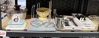 Overall view of lot on shelf showing salad spinner, colander, stands, trays and utensils
