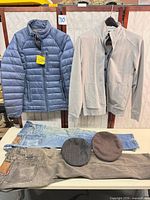 All six items laid out: two jackets hung, two jeans and two caps on table