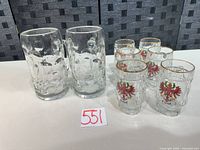 Group shot showing two large Hofbräuhaus München steins and six Tirol shot glasses