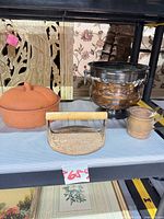 Full lot view showing terracotta apple baker, copper jardiniere, grill press handle, small Gregorian cup
