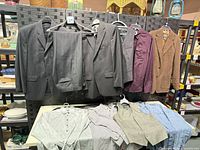 Overview of jackets, sport coat, dress shirts and vests displayed hanging and folded