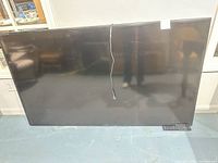 Front view of Sharp 70-inch TV with power cord and remote visible