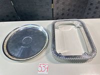 Round silver-plate Towle tray and rectangular Mariposa stand side by side