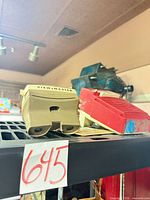 Beige View-Master viewer and red soundbar on shelf