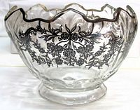 Front view of clear glass compote showing silver floral overlay and ruffled rim