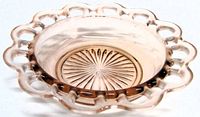 Angled view of pink glass bowl showing lace rim and sunburst base