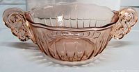 Front view of pink depression glass bowl showing scroll handles and ribbed body
