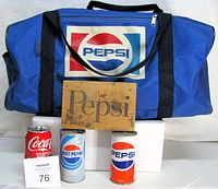 Group shot of duffel bag, wooden sign and two Pepsi cans
