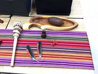 Props on striped mat: maraca, cacao pod, small figurines, feathers, tray
