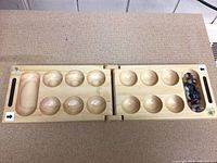 Full open view of wooden foldable Mancala board showing all pits and hinge