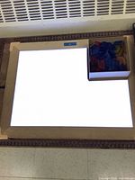 Light table powered on with box of translucent tiles visible