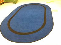 Full view of oval blue rug with black border