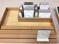Wooden rack with compartment holding multiple coloured clock face cards; one card displayed in front slot