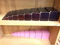 Brown stair blocks top shelf, pink tower cubes lower shelf displaying graduated sizes