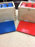 two wooden sound boxes open showing blue and red cylinders