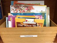 Wooden box containing assorted science picture books; visible title The Wheat We Eat