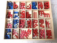 Open box showing assorted red, blue, pink, white wooden lowercase letters sorted in individual compartments