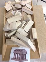 Tray filled with various unfinished wooden Parthenon blocks and reference photo