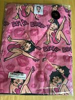 Front of packaged pink Betty Boop scrub top showing graphics and size tag