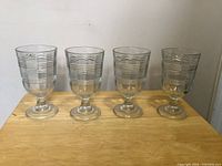 Four Martha Stewart optic banded glass goblets on table