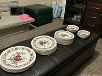 Stacked dinner, luncheon and salad plates plus bowls and saucers on bench