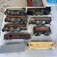 Nine vintage metal model train pieces laid out on table