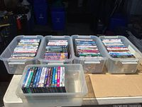Four large totes and one smaller tote filled with DVDs on table
