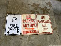 All three street signs side by side on floor