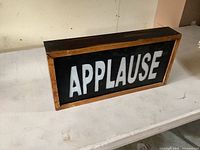 Front view showing full "APPLAUSE" text and oak frame